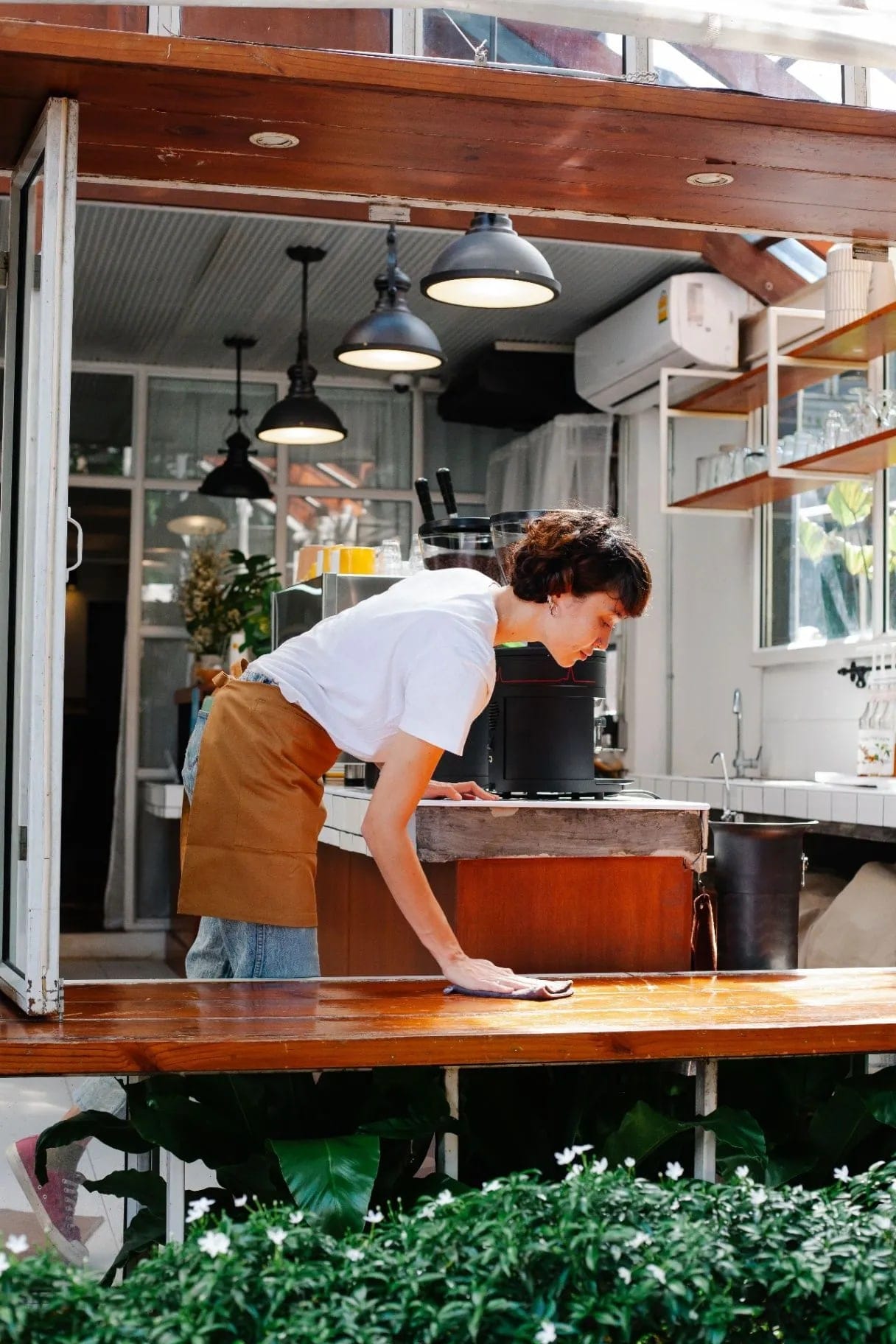 Woman in an apron wiping a cafe counter