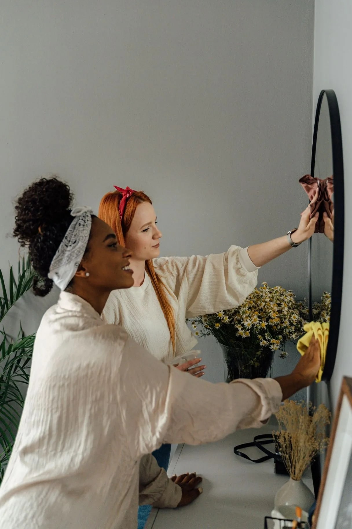 Two women cleaning a mirror together