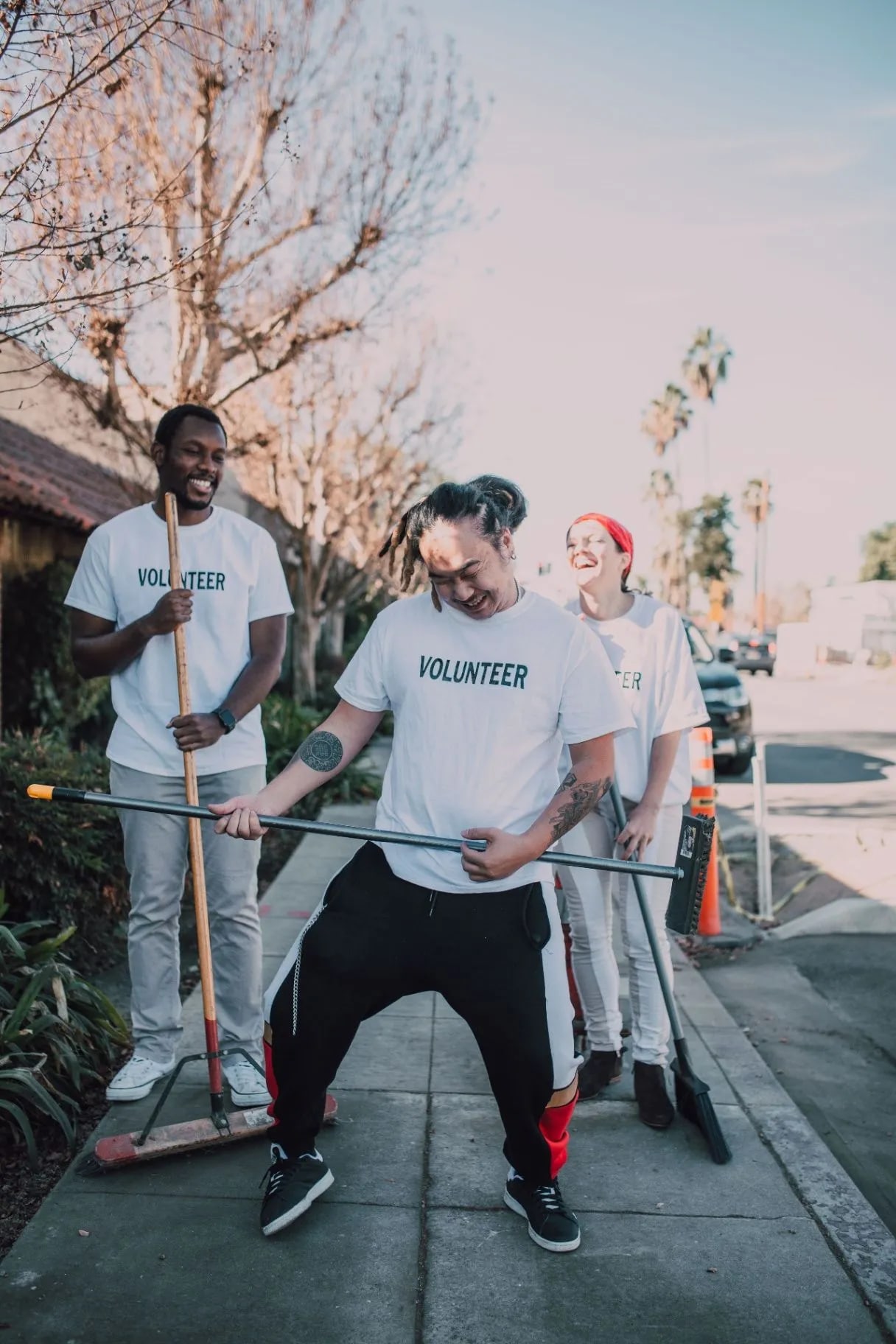 Cheerful cleaning crew with brooms and a mop on a sidewalk